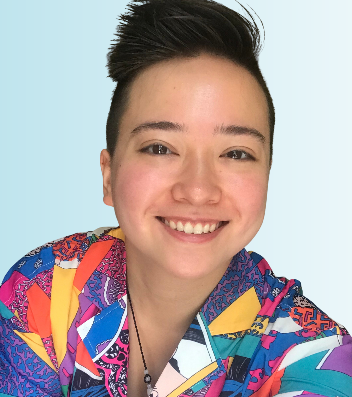 A photo of Max Tang, a biracial Chinese American donor-conceived person. Max has short dark hair, light skin, and is smiling in a colorful shirt.